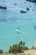man in white shirt riding on white and blue boat on blue sea during daytime
