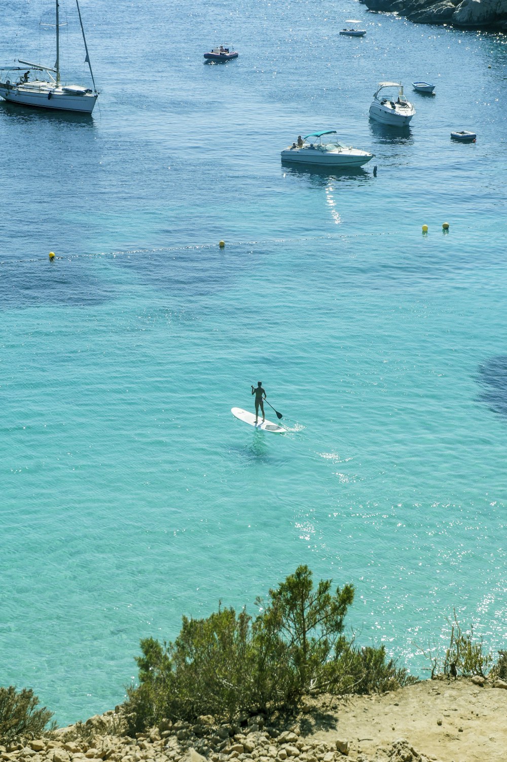 man in white shirt riding on white and blue boat on blue sea during daytime