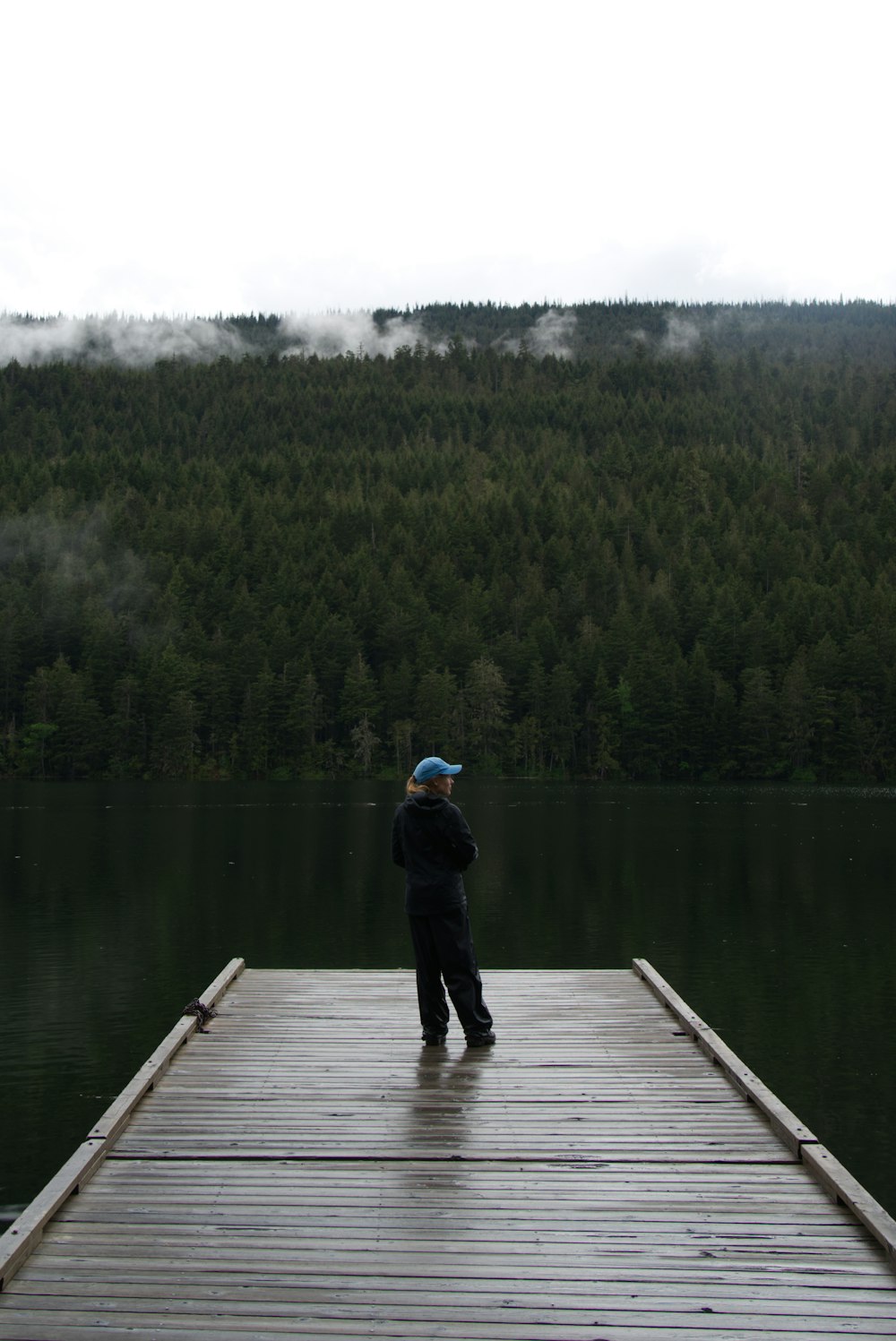 a young boy standing on a dock next to a body of water