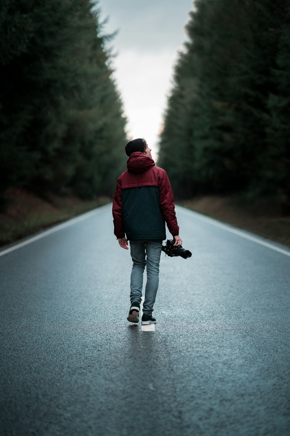 Hombre en chaqueta roja caminando por la carretera durante el día