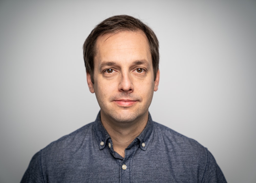 a man in a blue shirt is posing for a picture