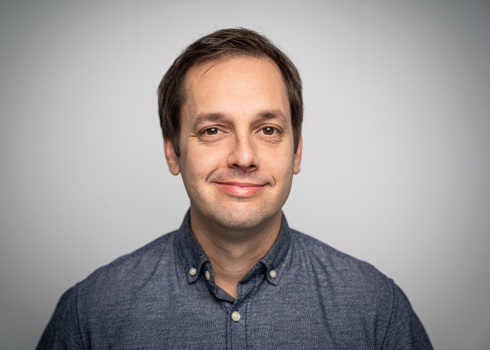 a man in a blue shirt smiling at the camera