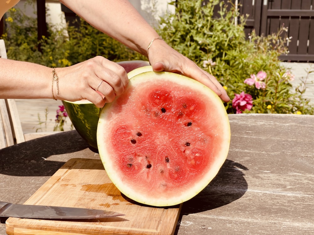 a person cutting up a watermelon on a cutting board