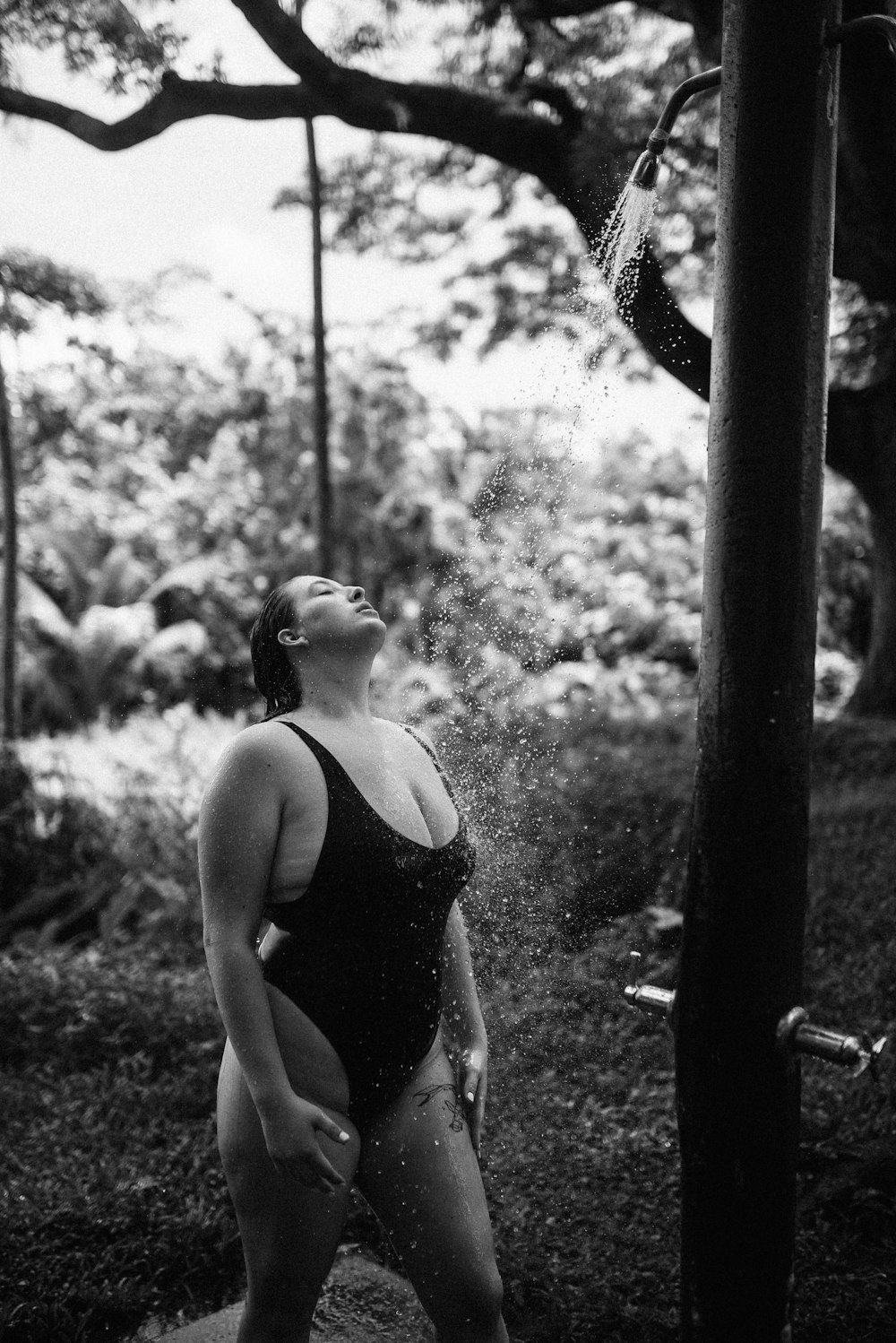 donna in canotta nera in piedi vicino all'albero
