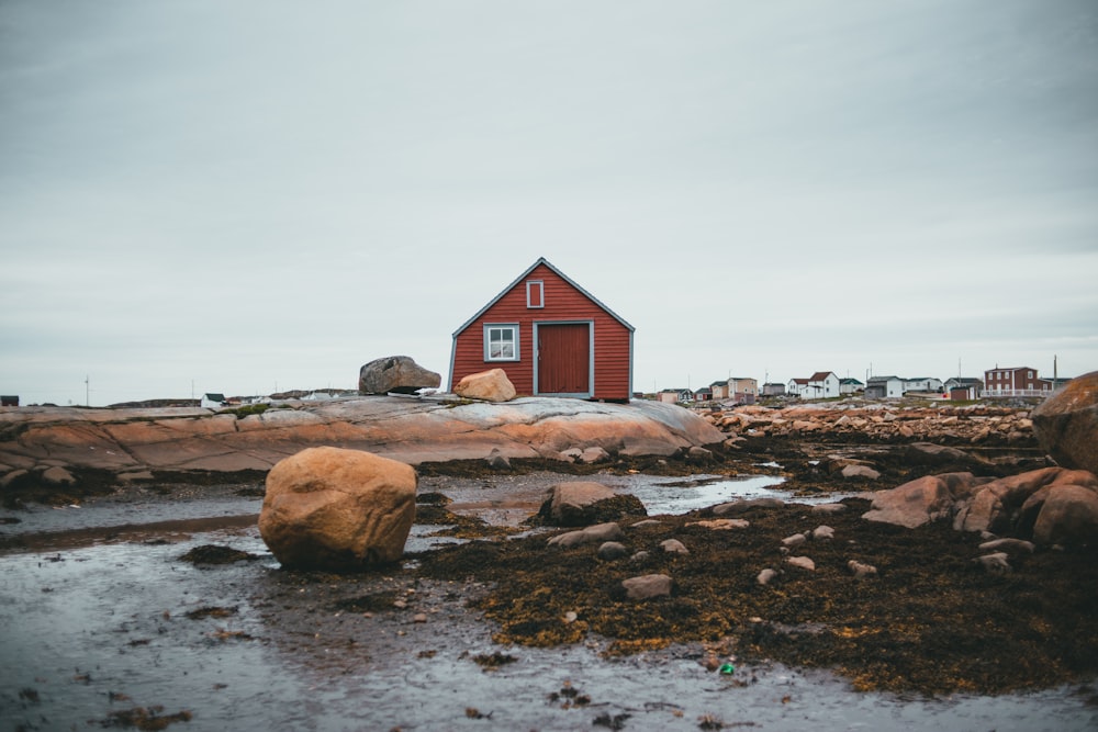 a red house sitting on top of a rocky beach