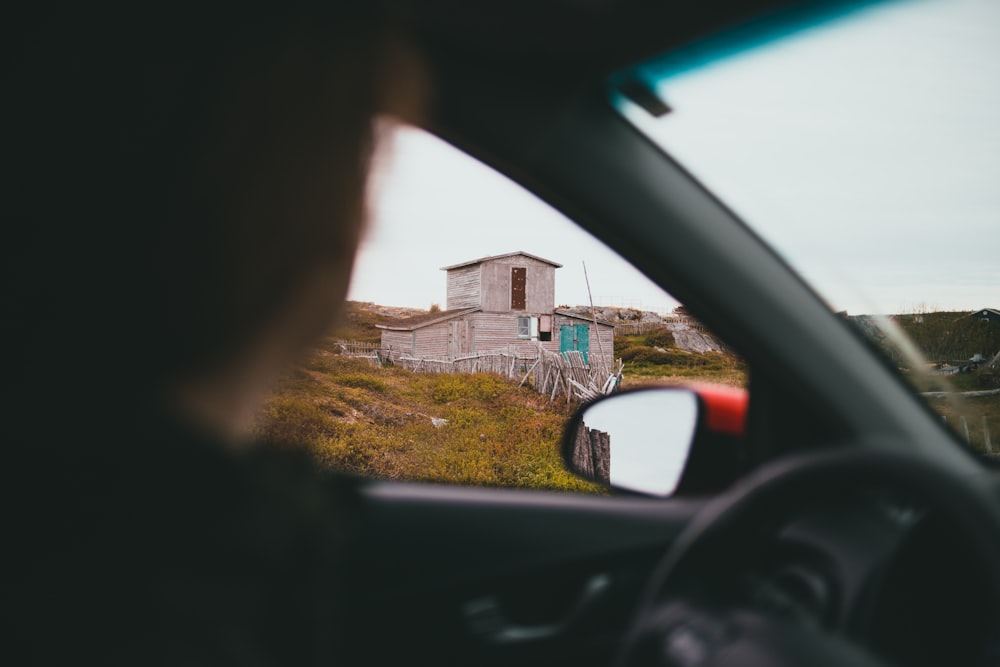 a person looking out of a car window at a house