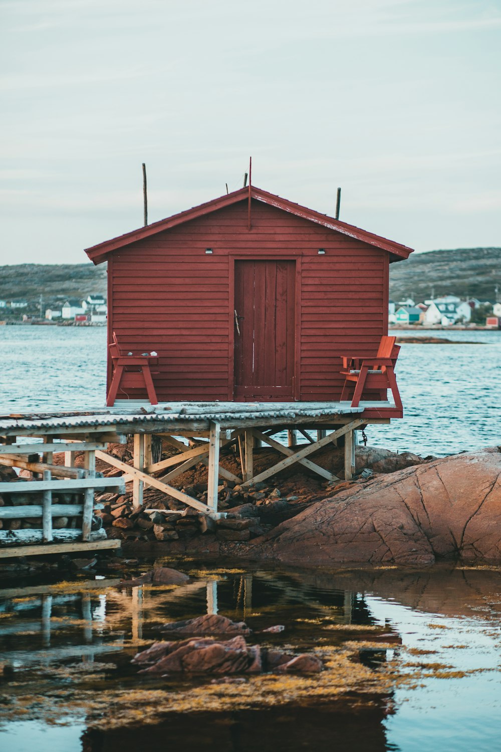 a red house sitting on top of a wooden dock