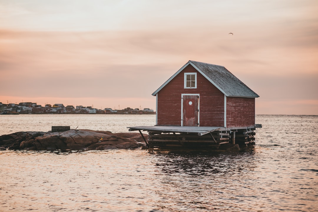 brown wooden house on body of water during sunset