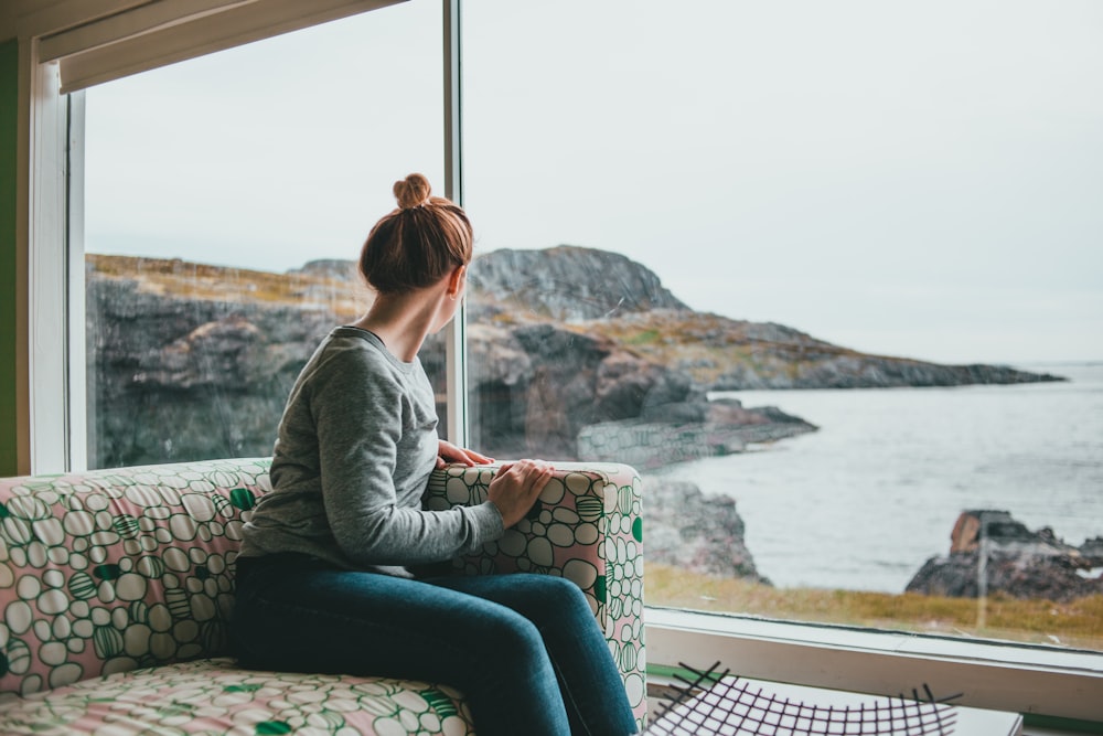 a woman sitting on a couch looking out a window