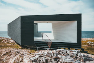 a black and white house sitting on top of a rocky hillside