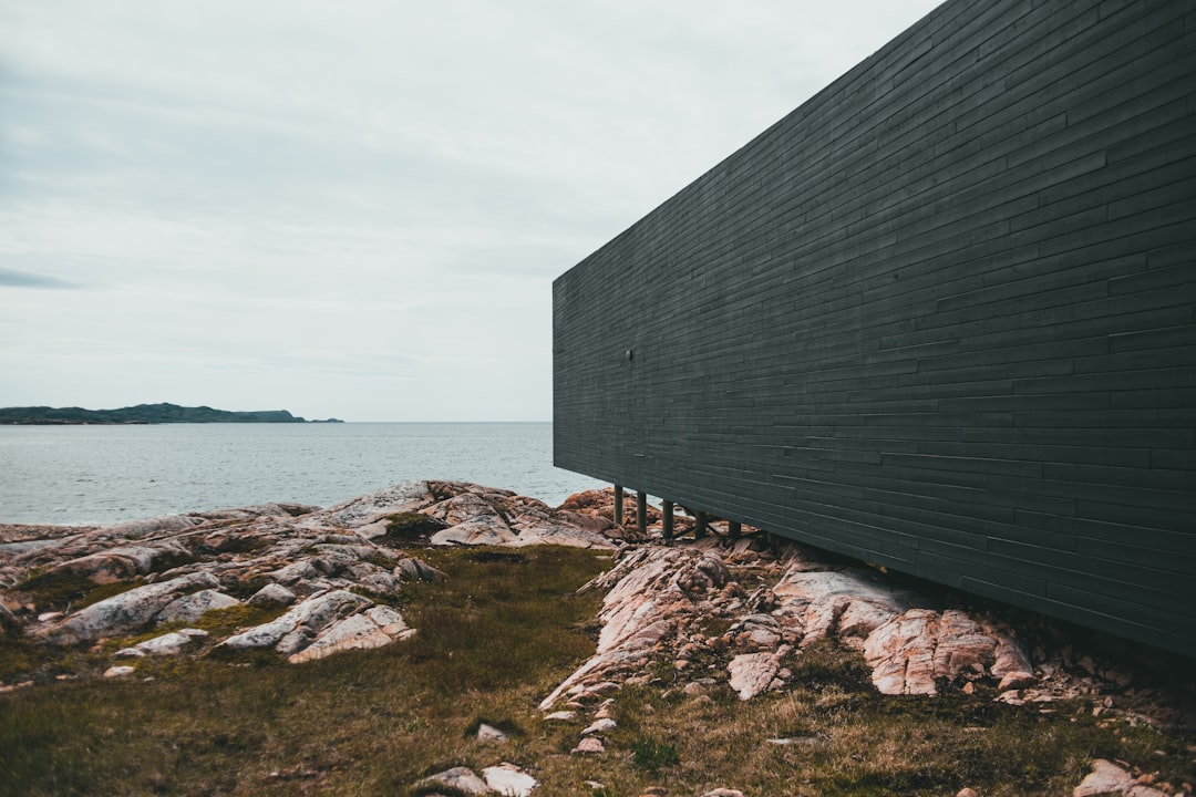 gray wooden house on brown rocky shore during daytime
