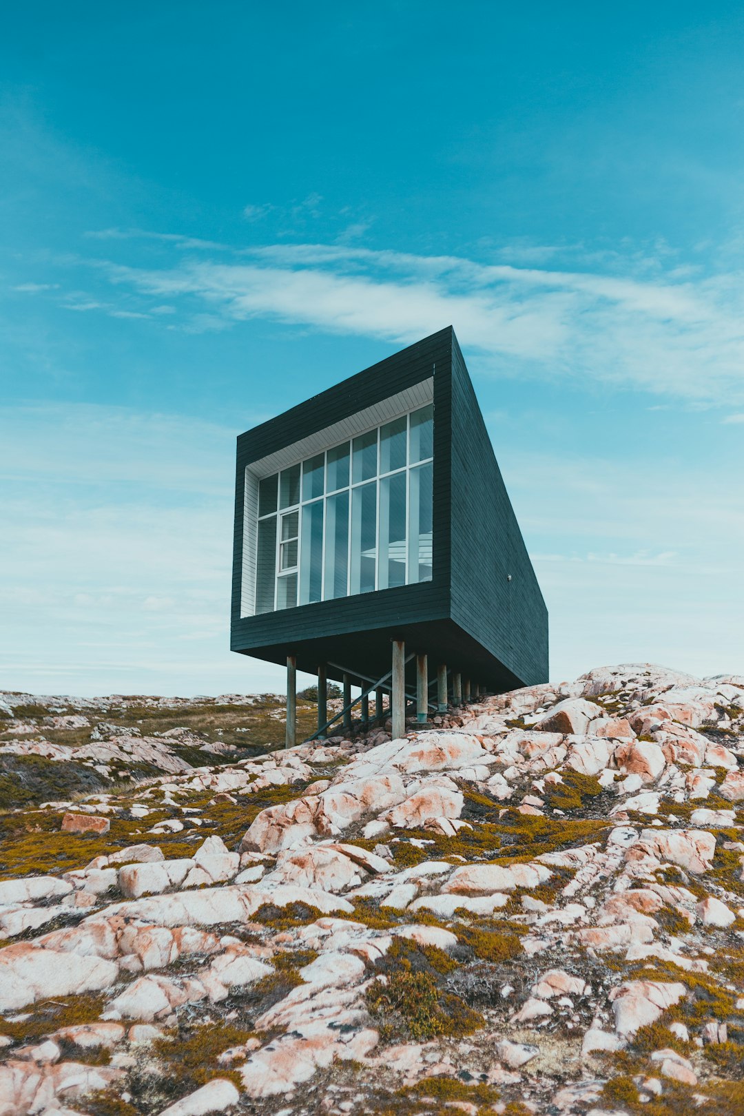 black and white wooden house on rocky ground under blue sky during daytime