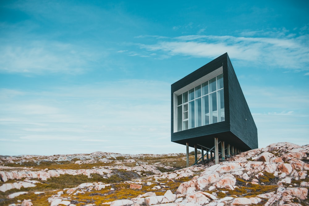 gray wooden house on rocky ground under blue sky during daytime