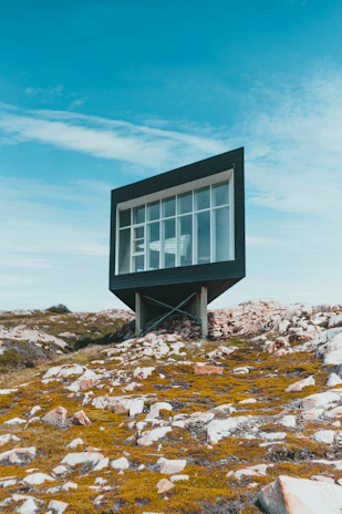 black and white wooden house on rocky hill under blue sky during daytime
