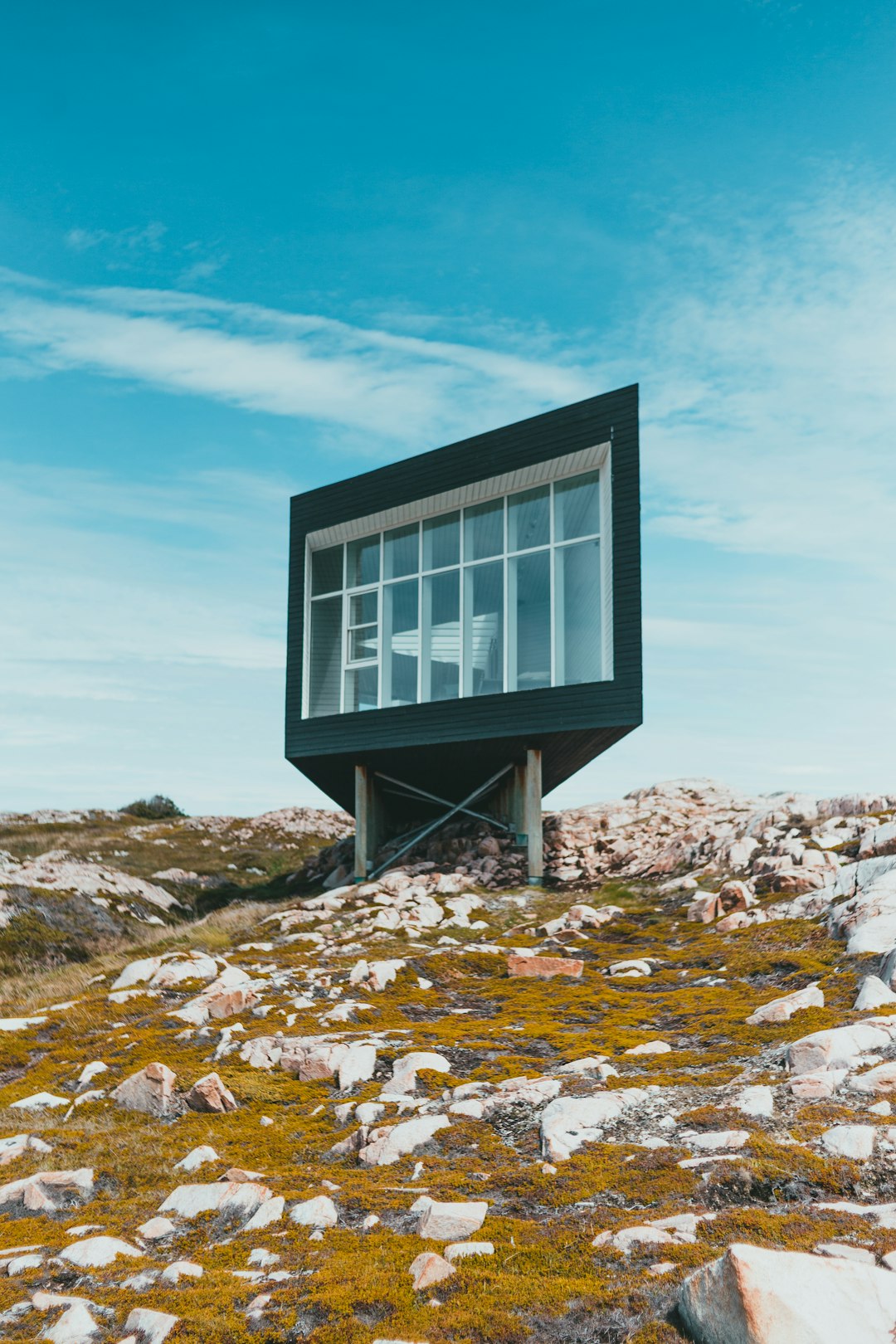 black and white wooden house on rocky hill under blue sky during daytime