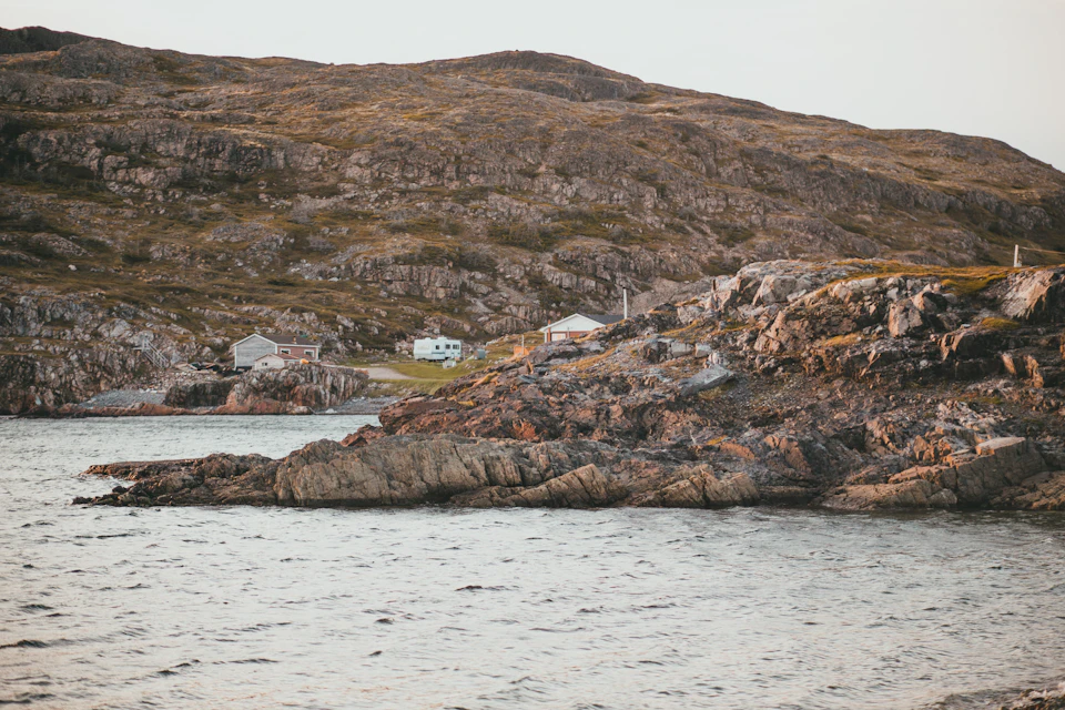 Serene coastal landscape with rocky cliff face overlooking calm and still body of water