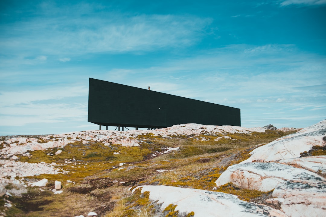 black and white concrete house on green grass field under blue sky during daytime