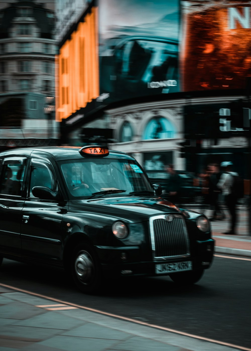 a black cab driving down a street next to tall buildings
