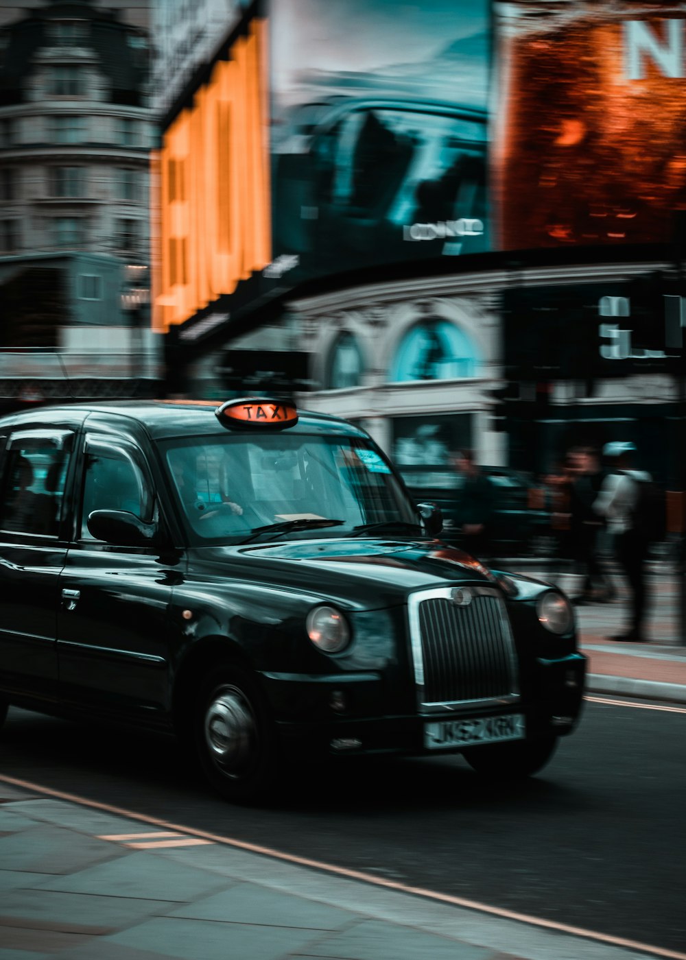 Un taxi noir roulant dans une rue à côté de grands immeubles