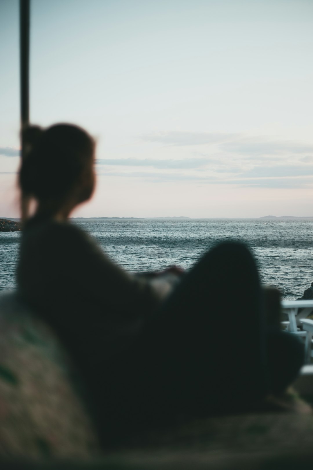 silhouette of woman sitting on chair looking at the sea during sunset