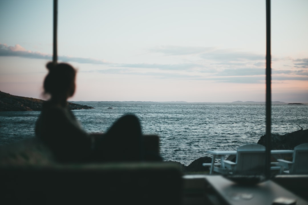 silhouette of 2 people sitting on chair near sea during sunset