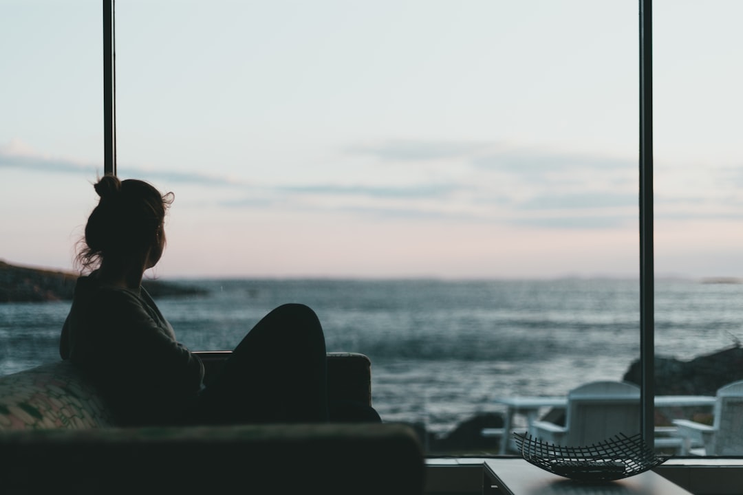 man sitting on a concrete bench looking at the sea during daytime