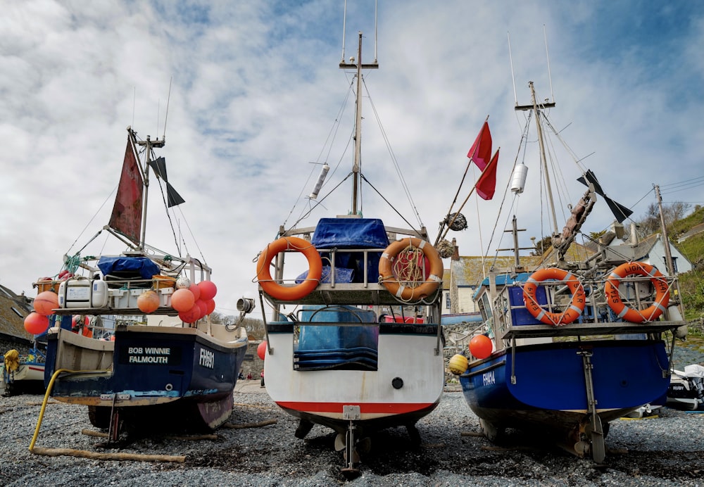 three boats sitting on top of a rocky beach