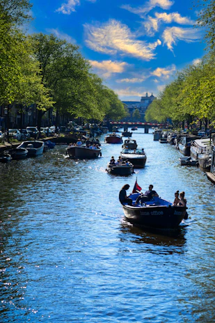 Colorful trajineras floating on the calm waters of Xochimilco surrounded by lush greenery under a bright sky.