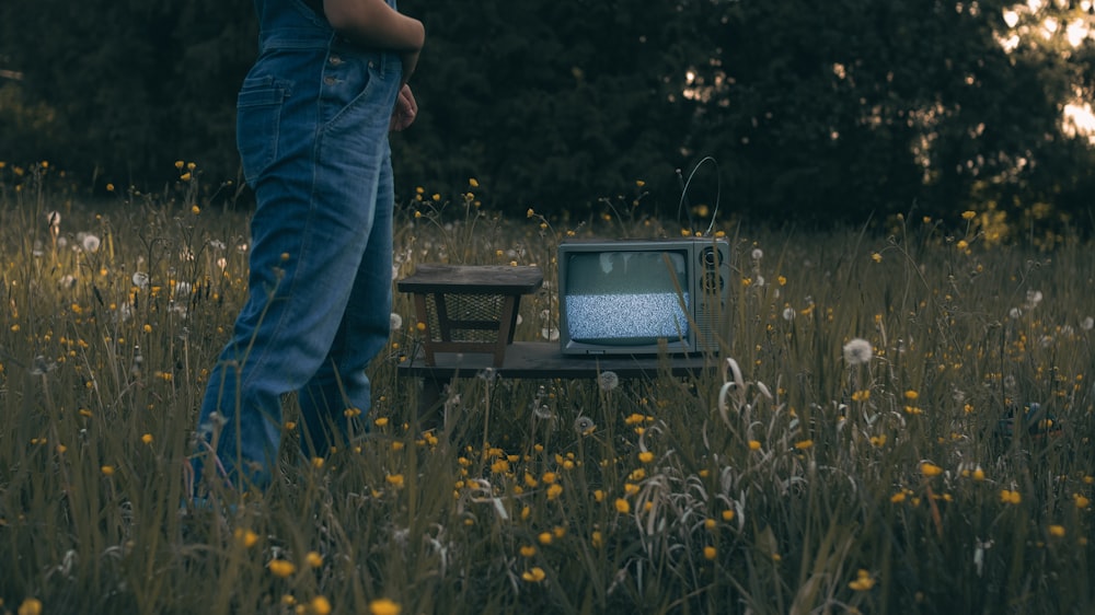 a man standing in a field next to a tv