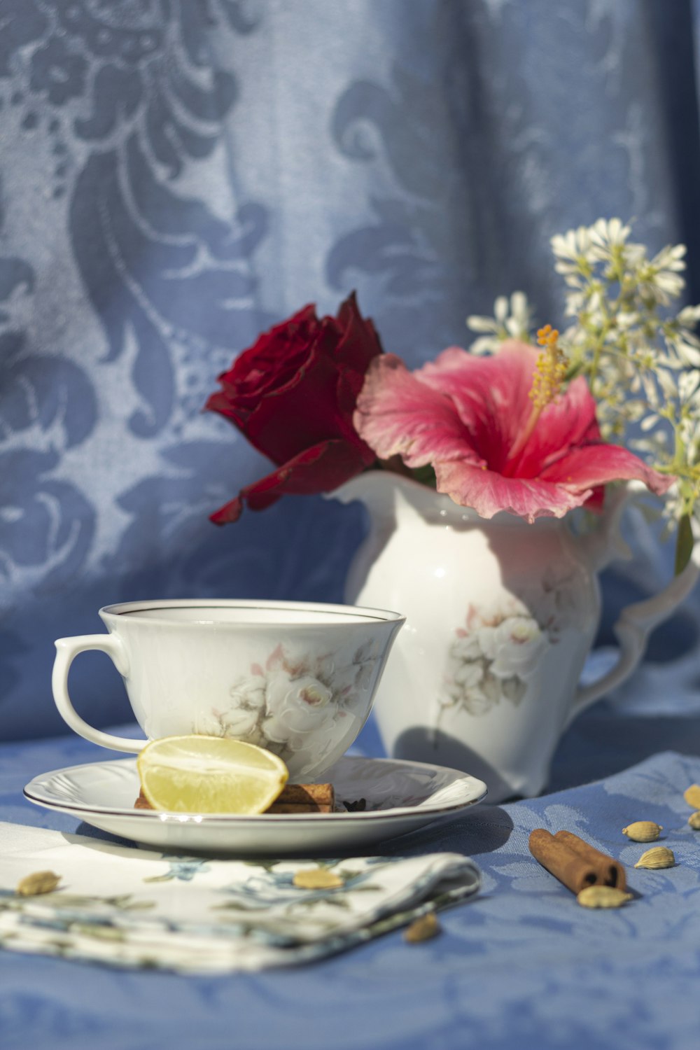 a tea cup and saucer with a flower in a vase