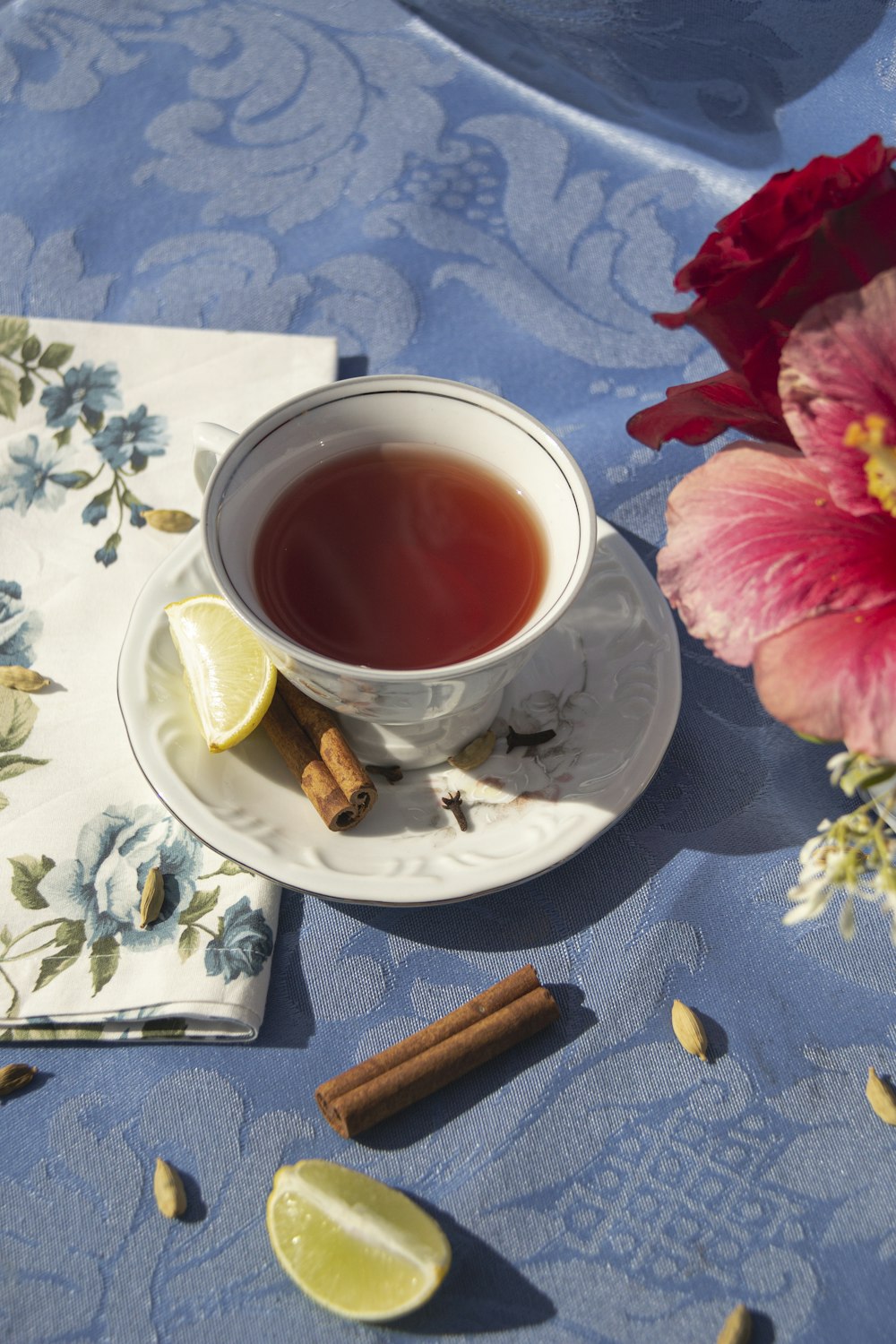 uma xícara de chá ao lado de um guardanapo e uma flor