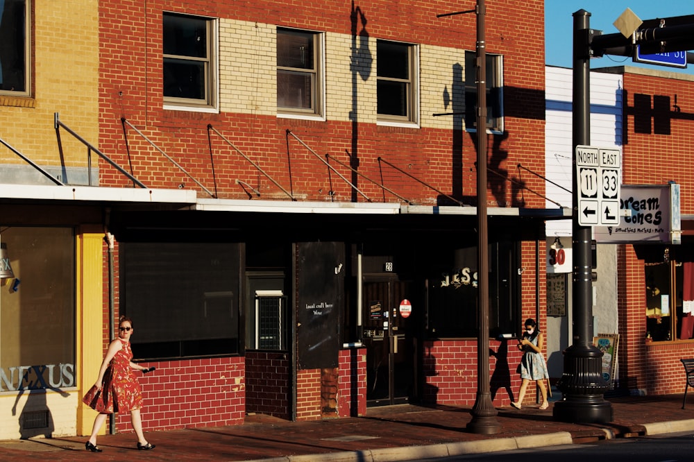 a woman in a red dress is walking down the street