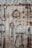 A variety of rusted horse tack, including stirrups and bits, hang on a corrugated metal wall. Each piece displays varying degrees of rust and wear, contrasting with the metallic background. The arrangement creates a rustic and vintage aesthetic.