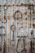A variety of rusted horse tack, including stirrups and bits, hang on a corrugated metal wall. Each piece displays varying degrees of rust and wear, contrasting with the metallic background. The arrangement creates a rustic and vintage aesthetic.