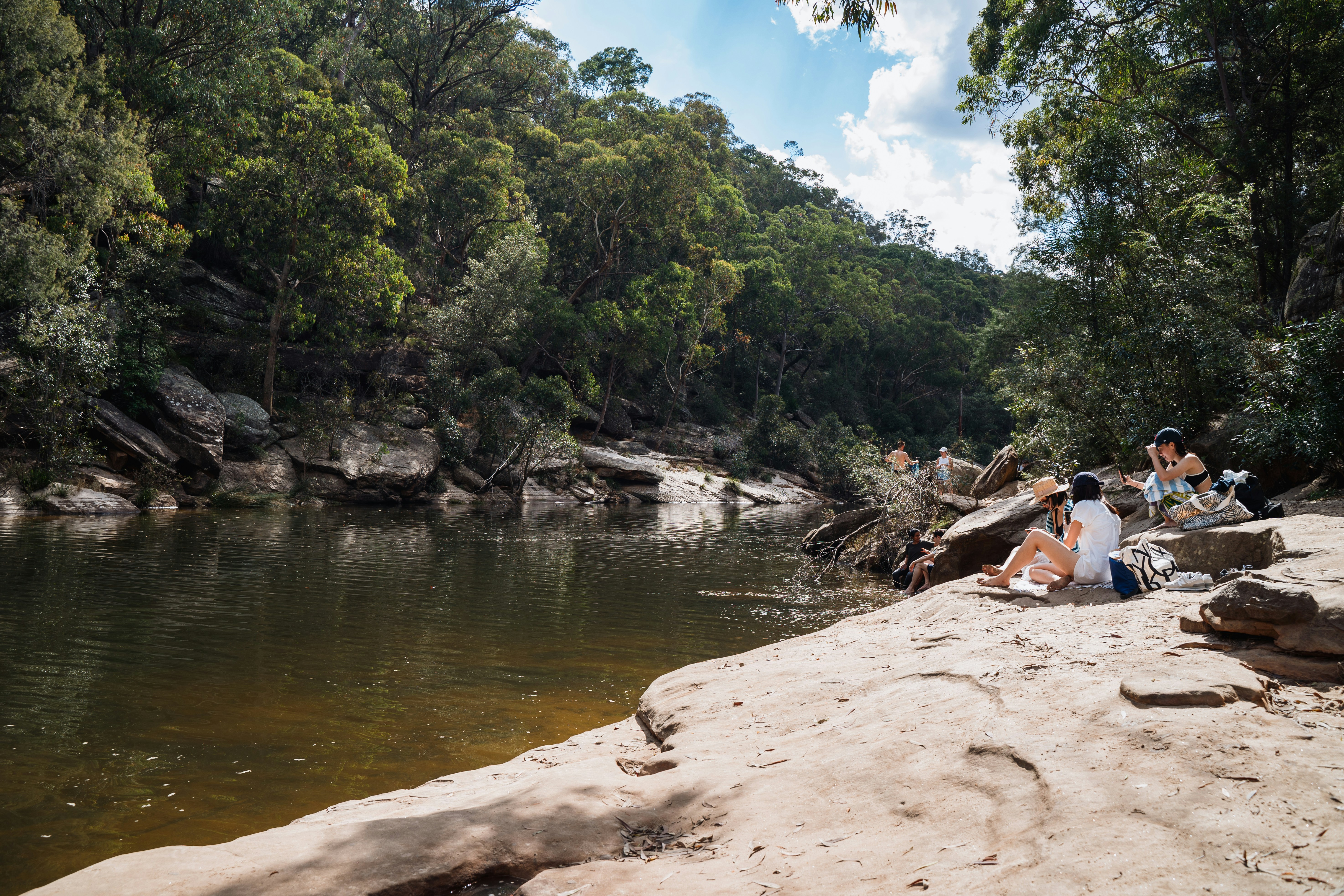 a group of people sitting on a rock next to a river
