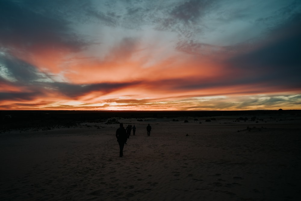 a group of people walking across a sandy beach