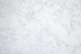 A white and gray marble texture with subtle veining patterns throughout, giving it a natural and elegant appearance.