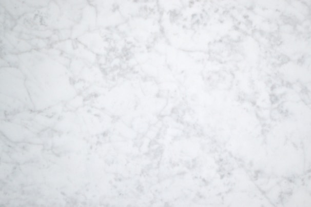 A white and gray marble texture with subtle veining patterns throughout, giving it a natural and elegant appearance.