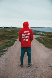man in gray hoodie standing on road during daytime