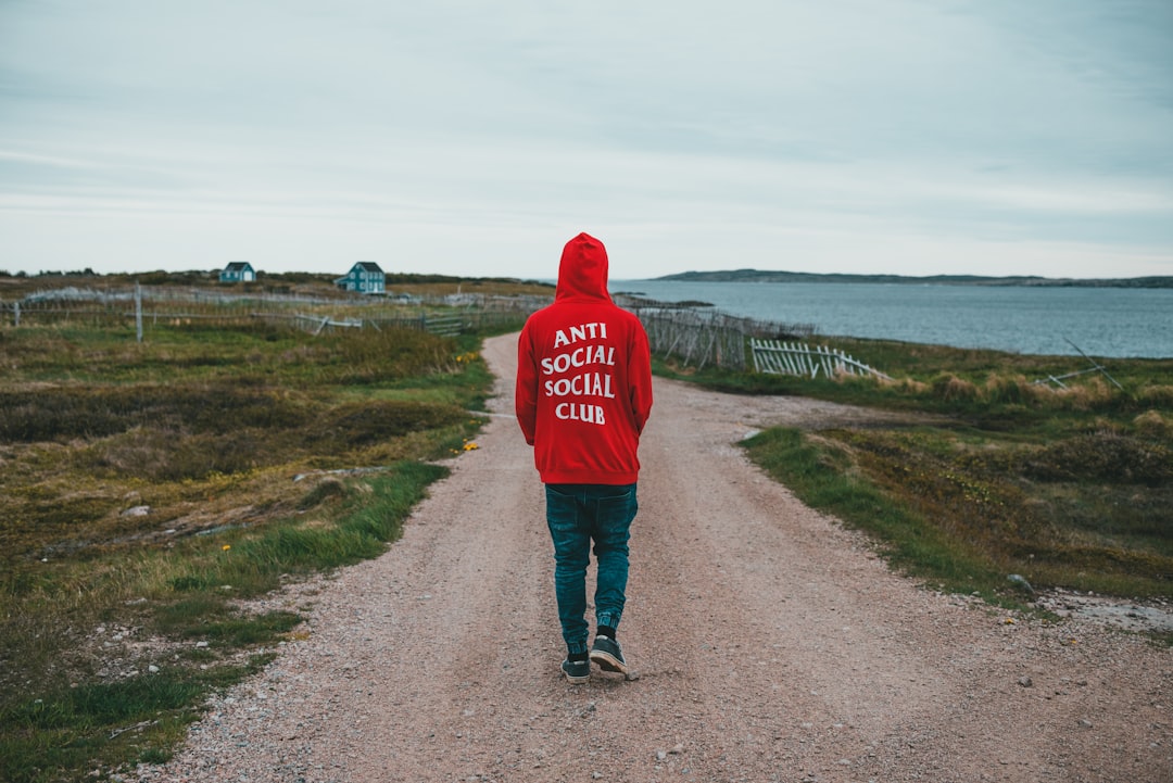 person in red hoodie walking on road during daytime