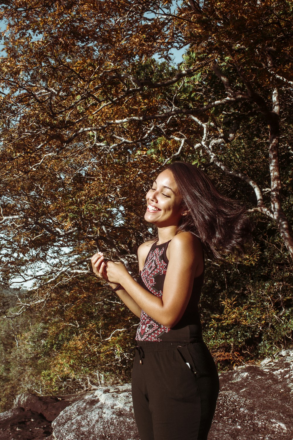 a woman standing in front of a tree and smiling