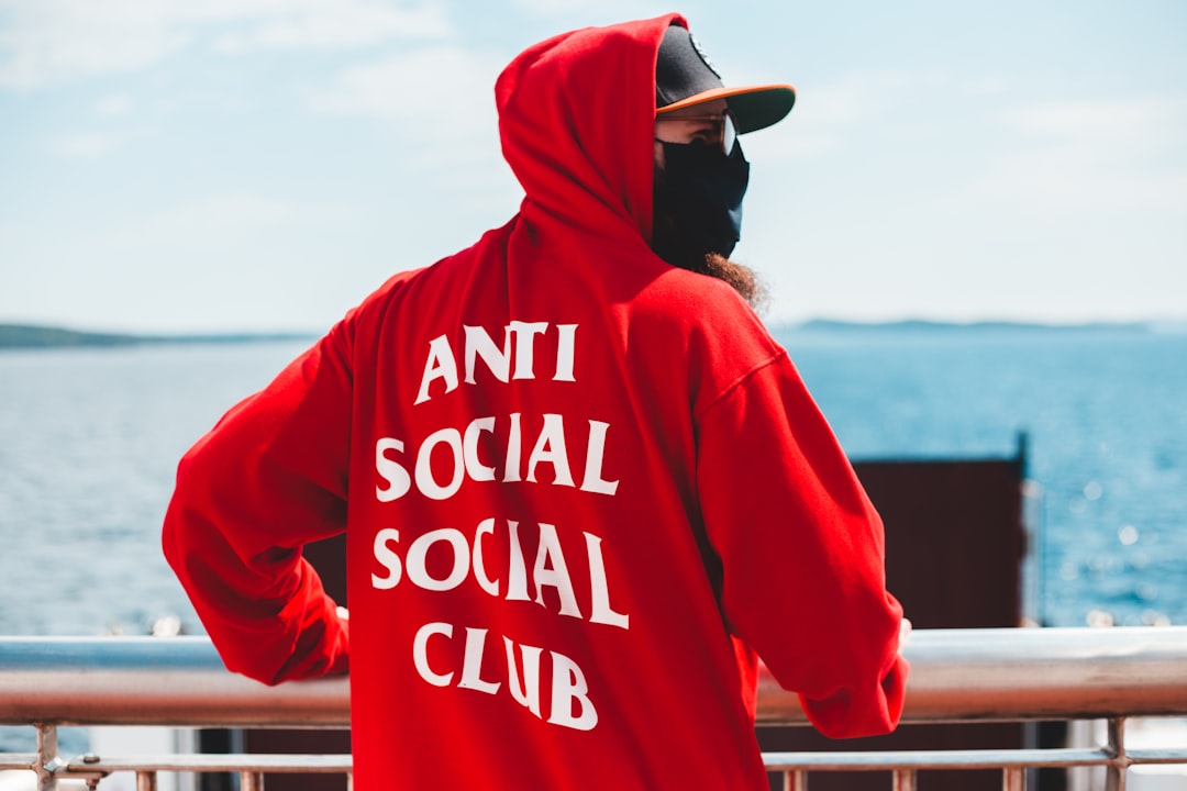 man in red and white hoodie wearing black cap