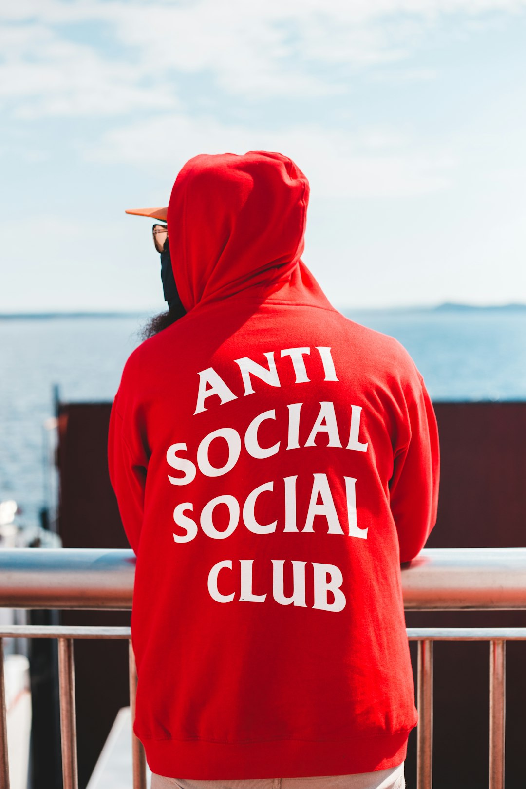 person in red and white hoodie standing near body of water during daytime