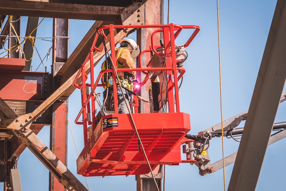 a man on a red lift working on a structure