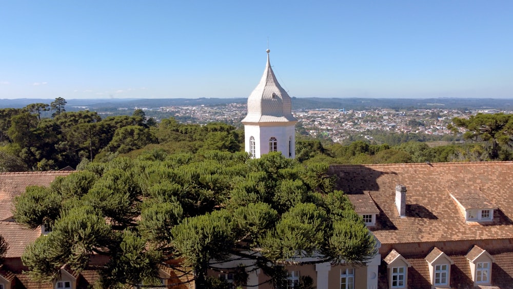 une vue d’un bâtiment avec un clocher et des arbres devant lui