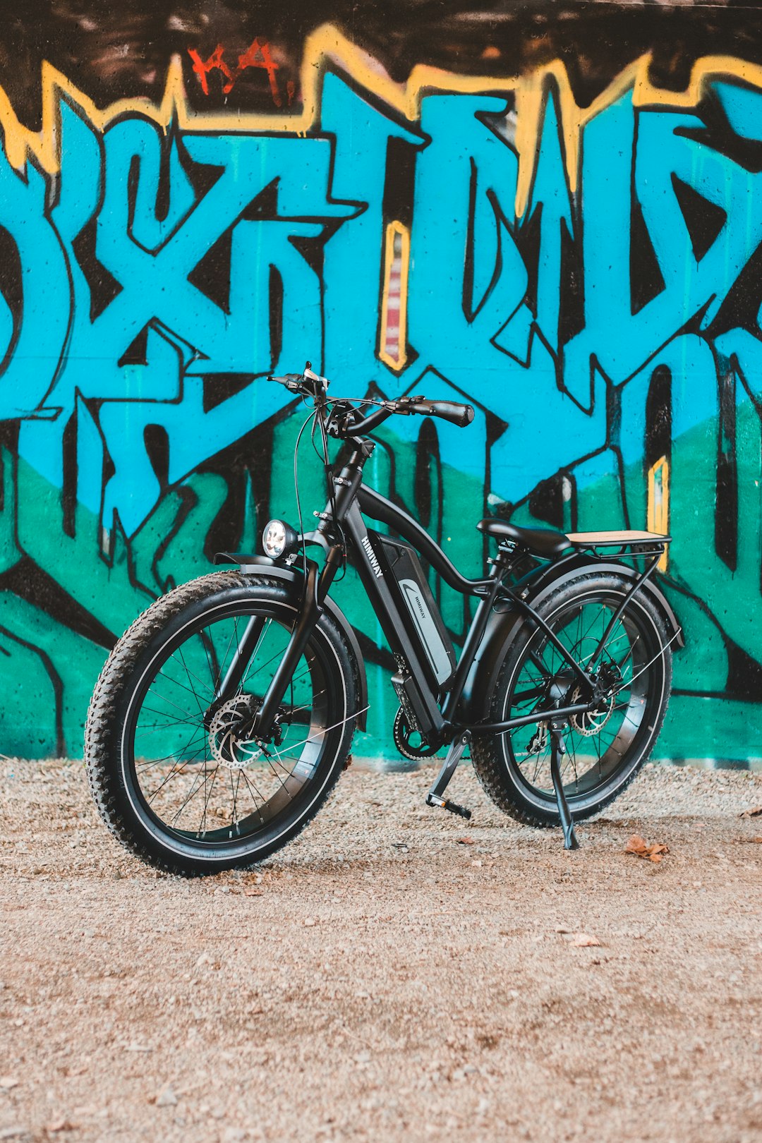 black and gray mountain bike leaning on wall with graffiti