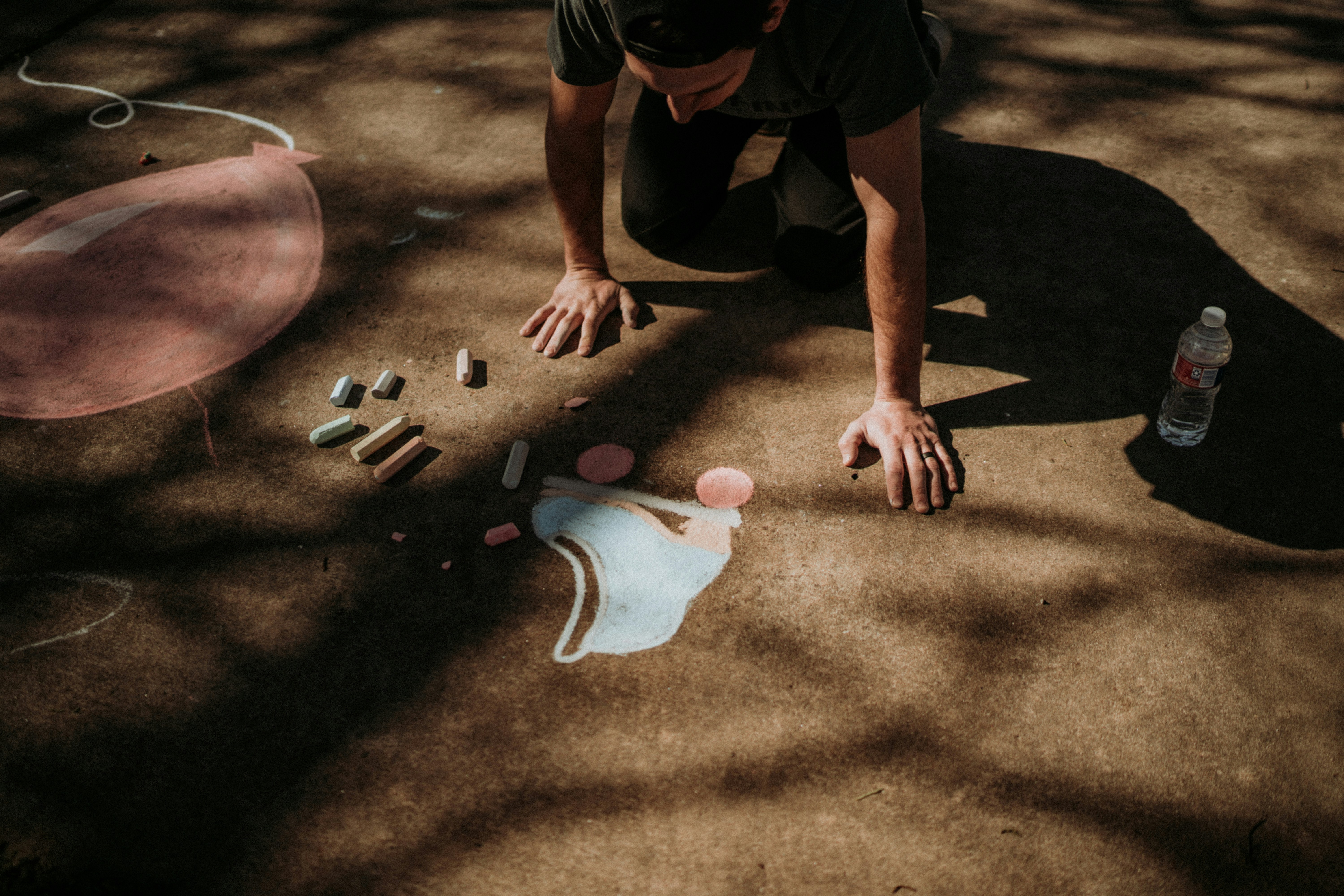 a man kneeling down on the ground next to a bottle of water