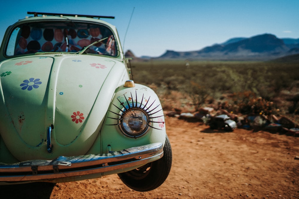 a green car parked on a dirt road