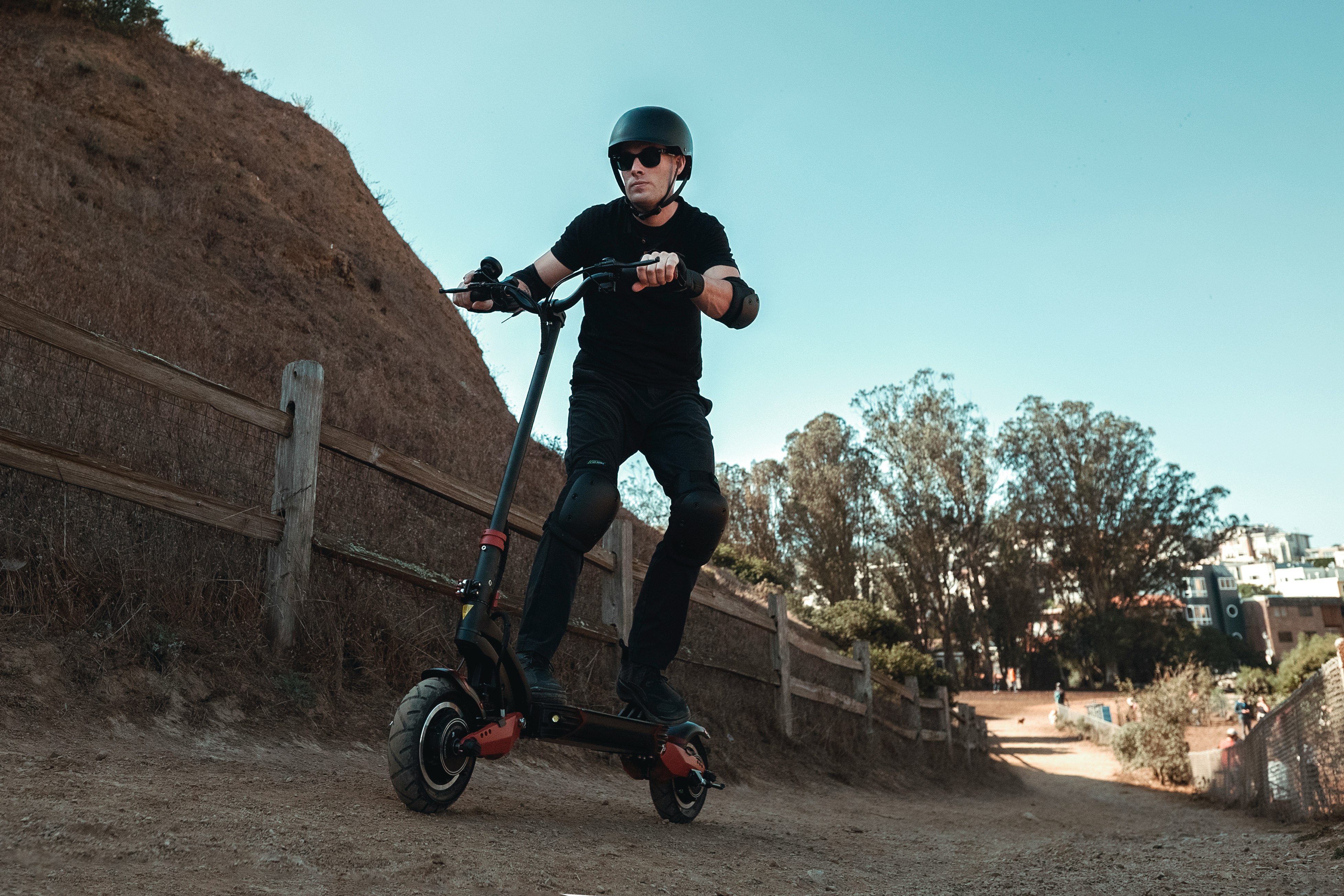 man in black jacket riding black and red kick scooter during daytime