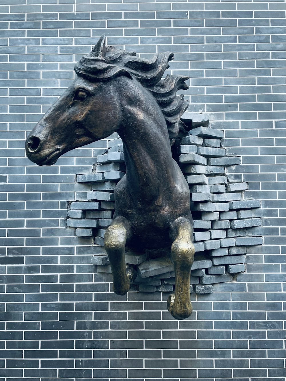 Una estatua de un caballo en una pared de ladrillo